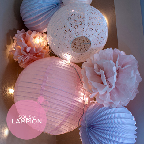 Pink nursery decor with paper lanterns and pompoms